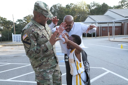 An elementary school student practices his scare tactic on Maj. Flake and Mr. Fowler during the Trunk or Treat event held at Church Street Elementary School where 3d MCDS Soldiers handed out candy from the back of a Humvee.