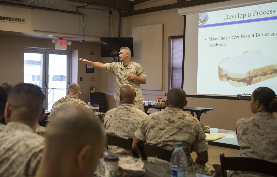 Chief Warrant Officer 4 Patrick M. Barnes, officer in charge, Admin Assist Unit, Marine Force Reserve, walks senior administrators through a practical application exercise 
that teaches process management by writing a procedure on how to make the perfect peanut butter sandwich during the 2016 Senior Administrator Symposium aboard Naval Air Station Joint Reserve Base Belle Chasse, La., Oct. 12-13, 2016. The symposium utilized instruction and practical application to help senior administrative personnel understand how and why the implementation of the Battalion Level Administrative Management initiative will improve Reserve units’ ability to pass MCAAT inspections. The initiative will mitigate the issues with the current system. (U.S. Marine Corps photo by Sgt. Sara Graham) 
