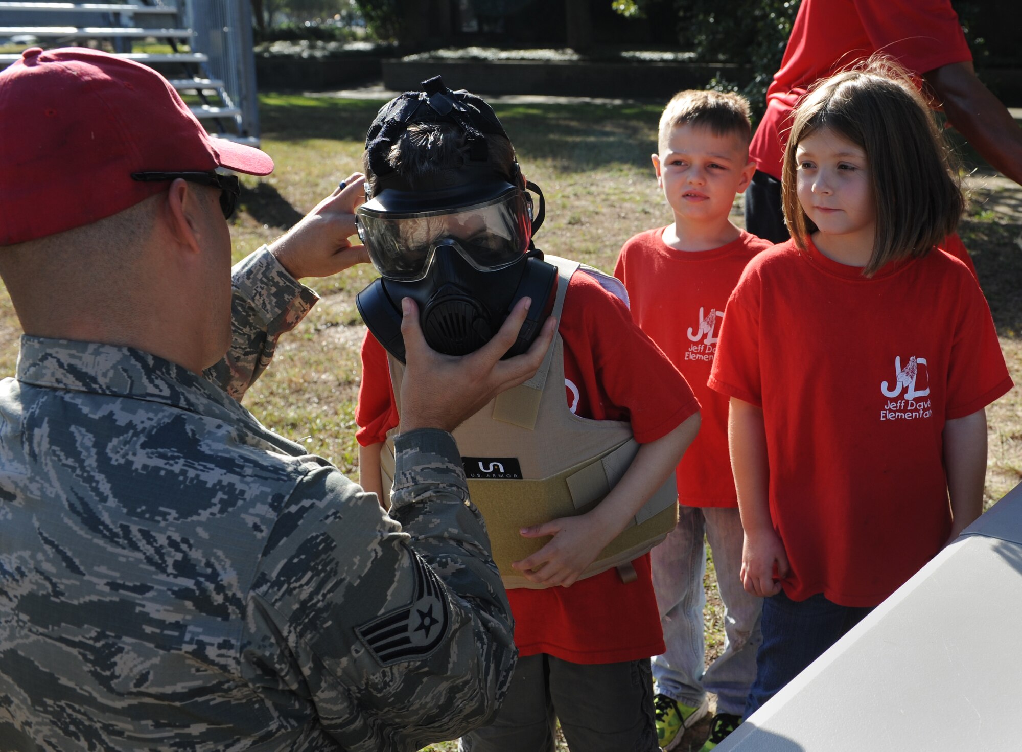 Staff Sgt. Matthew Keel, 81st Security Forces Squadron combat arms instructor, secures a gas mask on a Jeff Davis Elementary School first grader during a field trip to the 81st SFS Oct. 28, 2016, on Keesler Air Force Base, Miss. The children also toured the Keesler Fire Department where they received a demonstration on the proper wear of firefighter bunker gear and fire prevention safety information. (U.S. Air Force photo by Kemberly Groue/Released) 