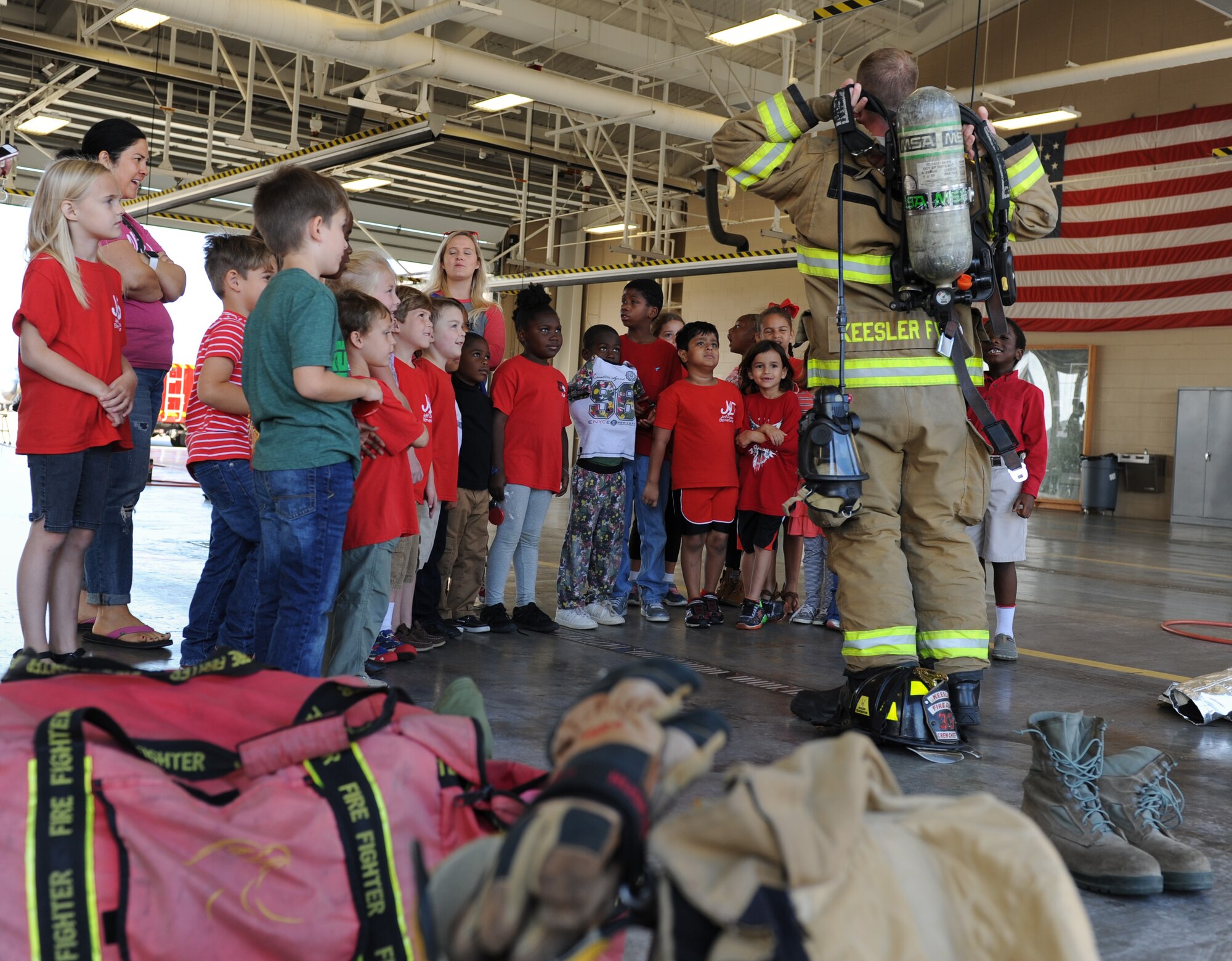 Jeff Davis Elementary School first graders watch as Tech. Sgt. Joshua Hartwell, 81st Infrastructure Division firefighter, demonstrates the proper wear of firefighter bunker gear during a field trip to the Keesler Fire Department Oct. 28, 2016, on Keesler Air Force Base, Miss. The children also toured the 81st Security Forces Squadron. (U.S. Air Force photo by Kemberly Groue/Released) 