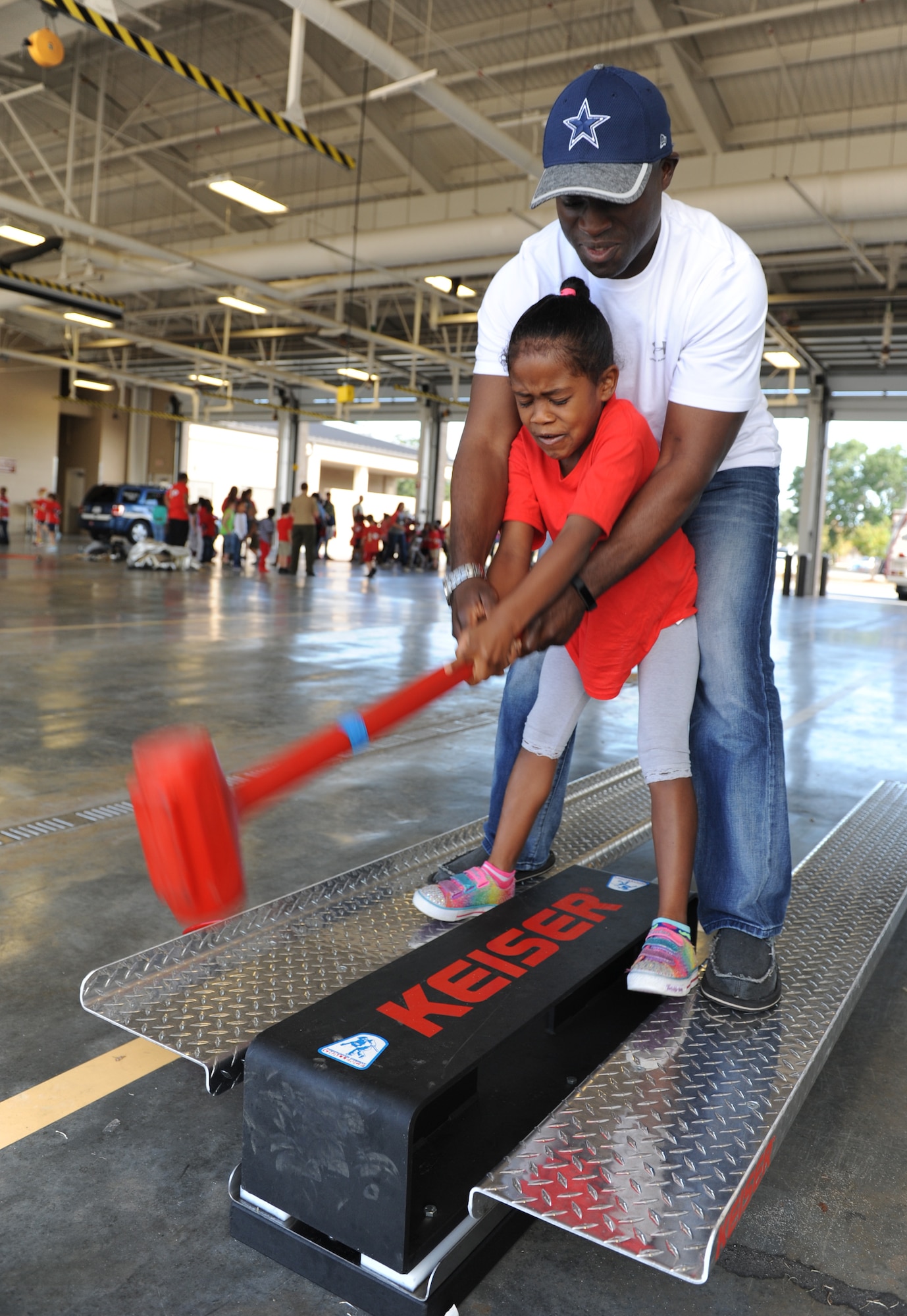 Senior Master Sgt. Larry Jackson, 81st Operations Support Flight tower controller chief, assists his daughter, Lilliana, with swinging a sledge hammer at the Keesler Fire Department during a Jeff Davis Elementary School first graders’ field trip Oct. 28, 2016, on Keesler Air Force Base, Miss. The children also toured the 81st Security Forces Squadron. (U.S. Air Force photo by Kemberly Groue/Released) 