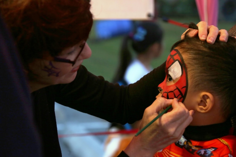 Chase, 3, right, gets his face painted during a Trunk or Treat event aboard Marine Corps Air Station Cherry Point, N.C., Oct. 27, 2016. Marine Corps Community Services hosted the Halloween-inspired event that included face painting; touch the truck displays; and a family glow dance party. Decorated trunks were judged and the highest-rated contestants received door prizes. (U.S. Marine Corps photo by Cpl. Jason Jimenez/Released)