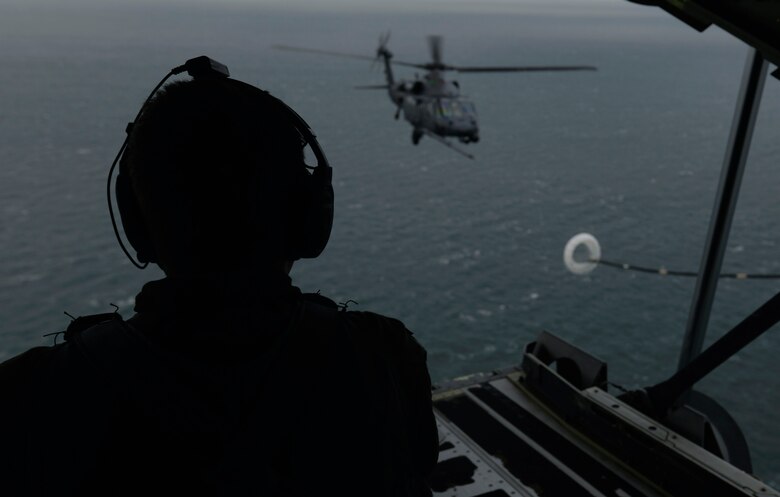 U.S. Air Force Staff Sgt. Tristian Lyons, 67th Special Operations Squadron MC-130J Commando ll loadmaster, watches as an HH-60G Pave Hawk helicopter assigned to the 56th Rescue Squadron RAF Lakenheath, England participates in a training mission Dec. 21, 2015, over the Norfolk Sea. The Pave Hawk has the capability to conduct day or night operations into hostile environments to recover downed aircrew or other isolated personnel during war. (U.A. Air Force photo by Senior Airman Victoria H. Taylor/Released)