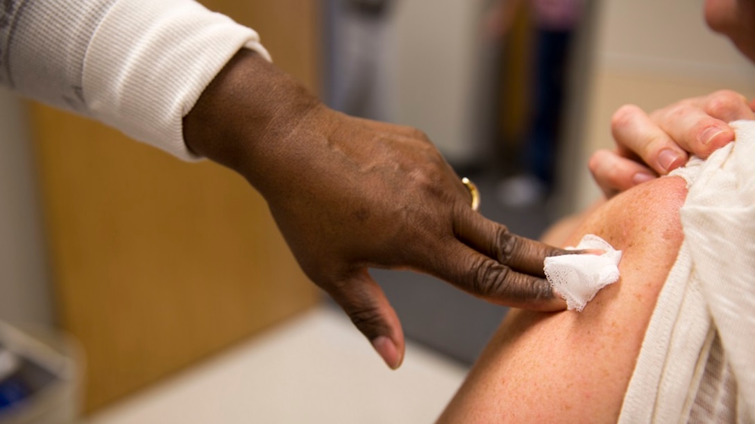 A healthcare professional puts pressure over the site of an injection after providing a flu vaccine to a patient during a community influenza vaccination event held by Naval Hospital Camp Lejeune aboard Marine Corps Base Camp Lejeune. 