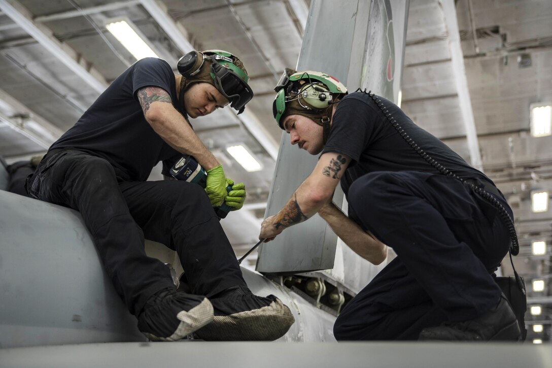 Navy Seaman Michael Williams, left, and Petty Officer 3rd Class Wesley Fritz install panels on an E/A-18G Growler, assigned to Electronic Attack Squadron 130, in the hangar bay of the aircraft carrier USS Dwight D. Eisenhower in the Persian Gulf, Oct. 27, 2016. The aircraft is assigned to Strike Fighter Squadron 32. The Eisenhower and its carrier strike group are deployed in support of Operation Inherent Resolve. Both sailors are aviation structural mechanics. Navy photo by Seaman Joshua Murray 