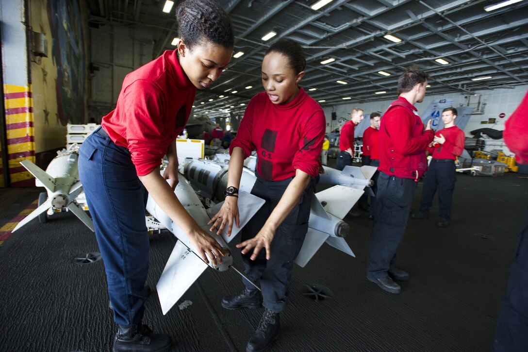 Navy Petty Officer 3rd Class Telecia Christian, left, trains Seaman Markia Lewis on proper handling of the GBU31 bomb in the hangar bay of the aircraft carrier USS Dwight D. Eisenhower in the Persian Gulf, Oct. 27, 2016. Christian and Markia are aviation ordnancemen. Navy photo by Petty Officer 3rd Class Andrew J. Sneeringer