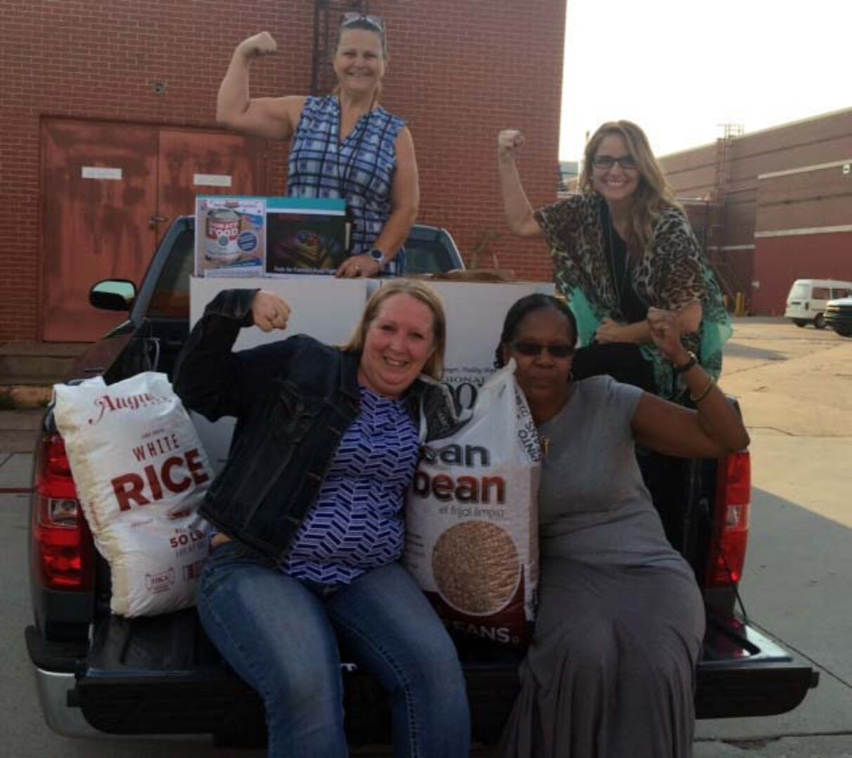 Defense Logistics Agency Aviation at Oklahoma City employees April Walker (bottom left), Ethlin Barnes-Carn (bottom right), Laurie Gillis (middle row, right) and Kim Winburn (top) show their muscles after loading boxes of food in support of the annual Feds Feed Families Program.  Both DLA Aviation and DLA Distribution employees together raised 2,456 pounds of food and donated it to the Regional Food Bank of Oklahoma. (courtesy photo)
