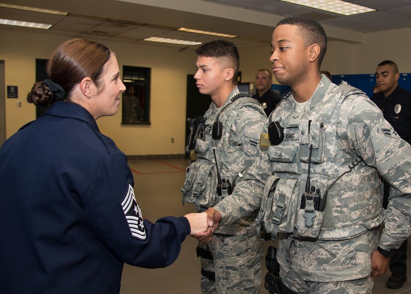 Hanscom Command Chief Master Sgt. Patricia L. Hickey presents her coin to Airman 1st Class Joshua King, right, and Airman 1st Class Christopher Allen, both entry controllers for the 66th Security Forces Squadron, during guard mount at Hanscom Air Force Base, Mass., Oct. 31. Both Airmen were recognized for their duty performance and for volunteering at a recent Combined Federal Campaign event. (U.S. Air Force photo by Mark Herlihy)