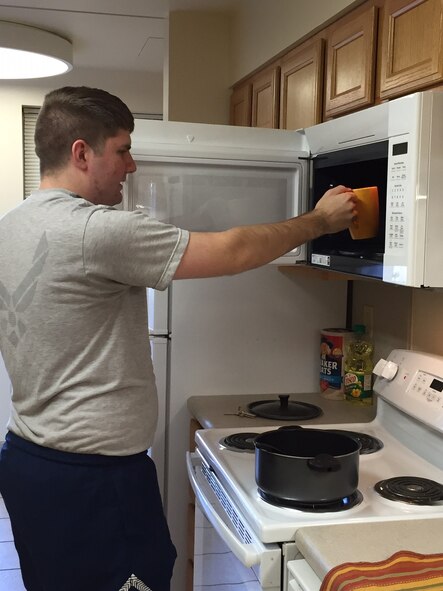 Airman 1st Class Charles Williamson, an air traffic controller in the 88th Operations Support Squadron, warms a cup of coffee in one of the 27 new combination microwave oven/stove units just installed in Bldg. 1216, Kittyhawk Center, Area A. A whole host of improvements to the dorms is making life easier for young Airmen. (Skywrighter photo/Amy Rollins)