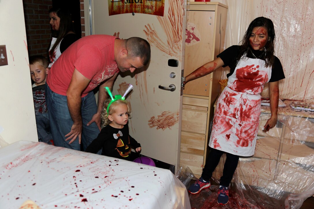 Abby, 2, center, is let into a butcher shop-themed room by Lance Cpl. Jailene Burciaga during a Haunted Barracks event aboard Marine Corps Air Station Cherry Point, N.C., Oct. 28, 2016. Marine Wing Headquarters Squadron 2 hosted the event to give Marines living in the barracks an opportunity to celebrate Halloween with other MWHS-2 Marines and their families. Children went door-to-door with their parents and received candy from the Marines. Burciaga is an embarkation specialist with MWHS-2.