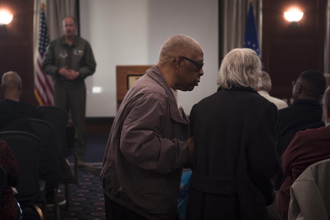 A retired couple look for their seats during Retiree Appreciation Day on Joint Base Andrews, Md., Oct. 29, 2016, while Col. E. John Teichert, 11th Wing and JBA commander, speaks. The event included a health fair and flu shots, and also gave information on Tricare, recreation activities, and more. (U.S. Air Force photo by Senior Airman Mariah Haddenham)