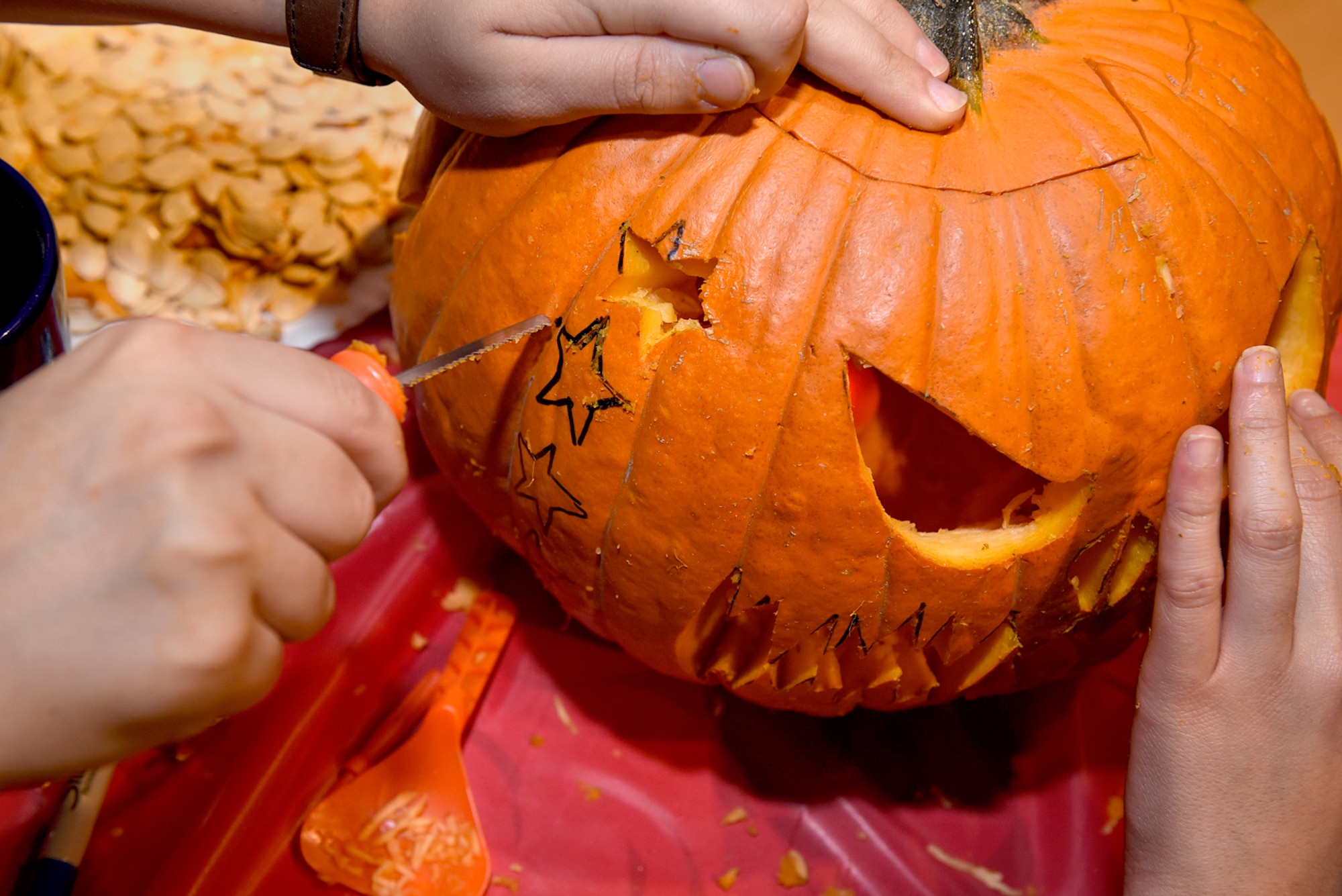 PETERSON AIR FORCE BASE, Colo. – Participants in the 4th Annual Pumpkin Carving Contest carve out starts to add to their submission at the Eclipse Cyber Café on Peterson Air Force Base, Colo., Oct. 26, 2016. The team went on to win the contest. (U.S. Air Force photo by Senior Airman Rose Gudex)