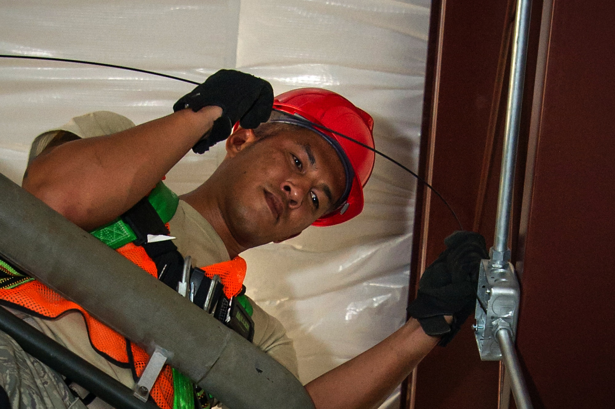 Tech. Sgt. Setthapone Khamphengphetl, a 560th RHS electrical systems specialist, fishes electrical wire through conduit for ceiling lights in his squadron's newest constrcution project at Joint Base Charleston Aug. 17. Khamphengphetle is currently looking for a civilian job after earning his bachlor of science in electical engineering. Members of the 560th RHS and the 628th Civil Engineer Squadron at Joint Base Charleston, Sout Carolina and the 555th RHS from Nellis Air Force Base, Nevada, and the 567th RHS from Seymour Johnson Air Force Base, North Carolina joined forces at Joint Base Charleston to build a 4,800 square-foot preengineered  building building to store construction equipment and gear.  Rapid Engineer Deployable, Heavy Operational Repair Squadron, Engineer (RED HORSE) squadrons provide the Air Force with a highly mobile civil engineering capability in support of contingency and special operations worldwide. They are self-sufficient, mobile squadrons that provide heavy construction support such as runway/facility construction, electrical upgrades, and equipment transport when requirements exceed normal base civil engineer capabilities and where Army engineer support is not readily available. (U.S. Air Force Photo by Master Sgt. Shane Ellis)