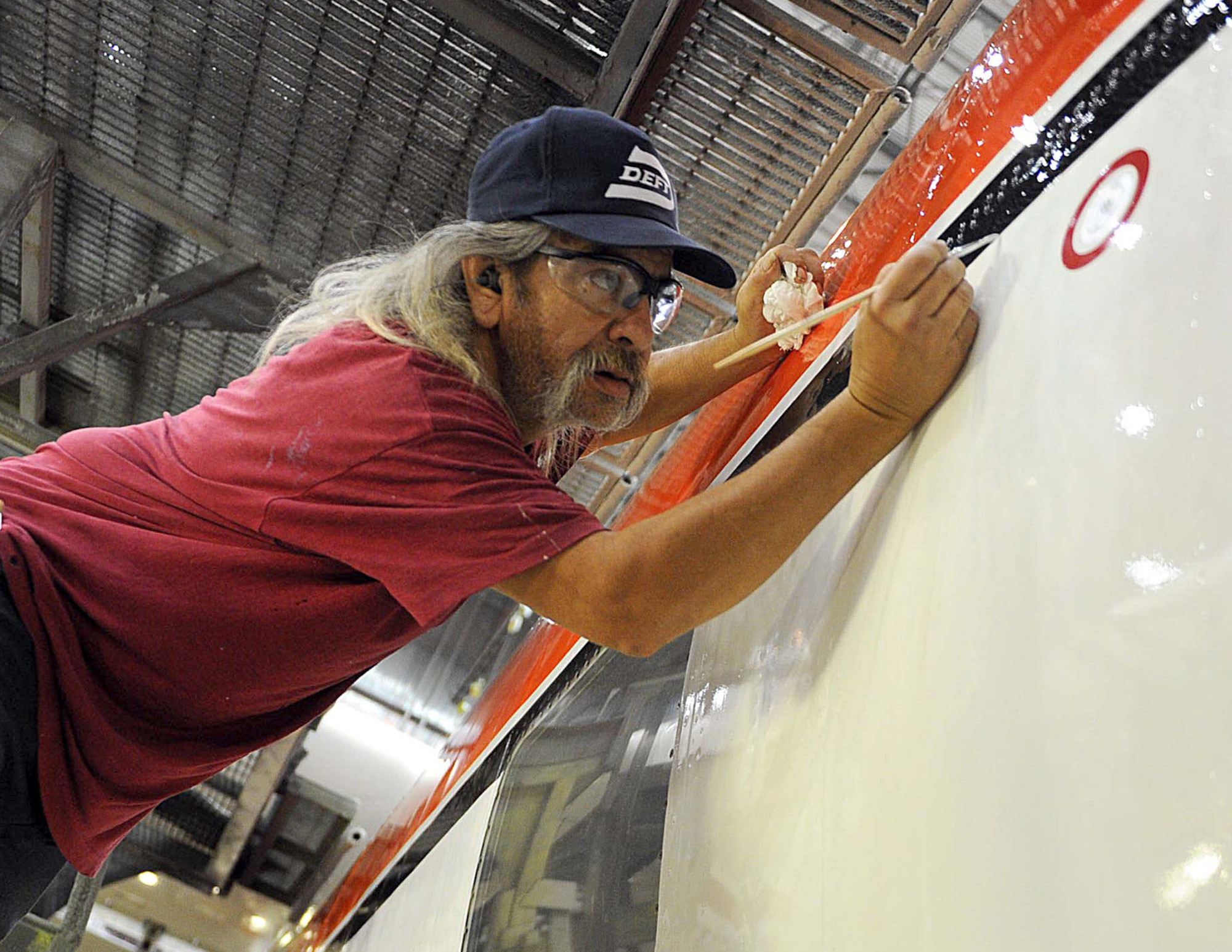 Sam Vigil, 402nd Aircraft Maintenance Support Squadron aircraft painter, touches up paint on a Coast Guard C-130H recently modified for transfer to the U.S. Forest Service. (U.S. Air Force photo by Tommie Horton)