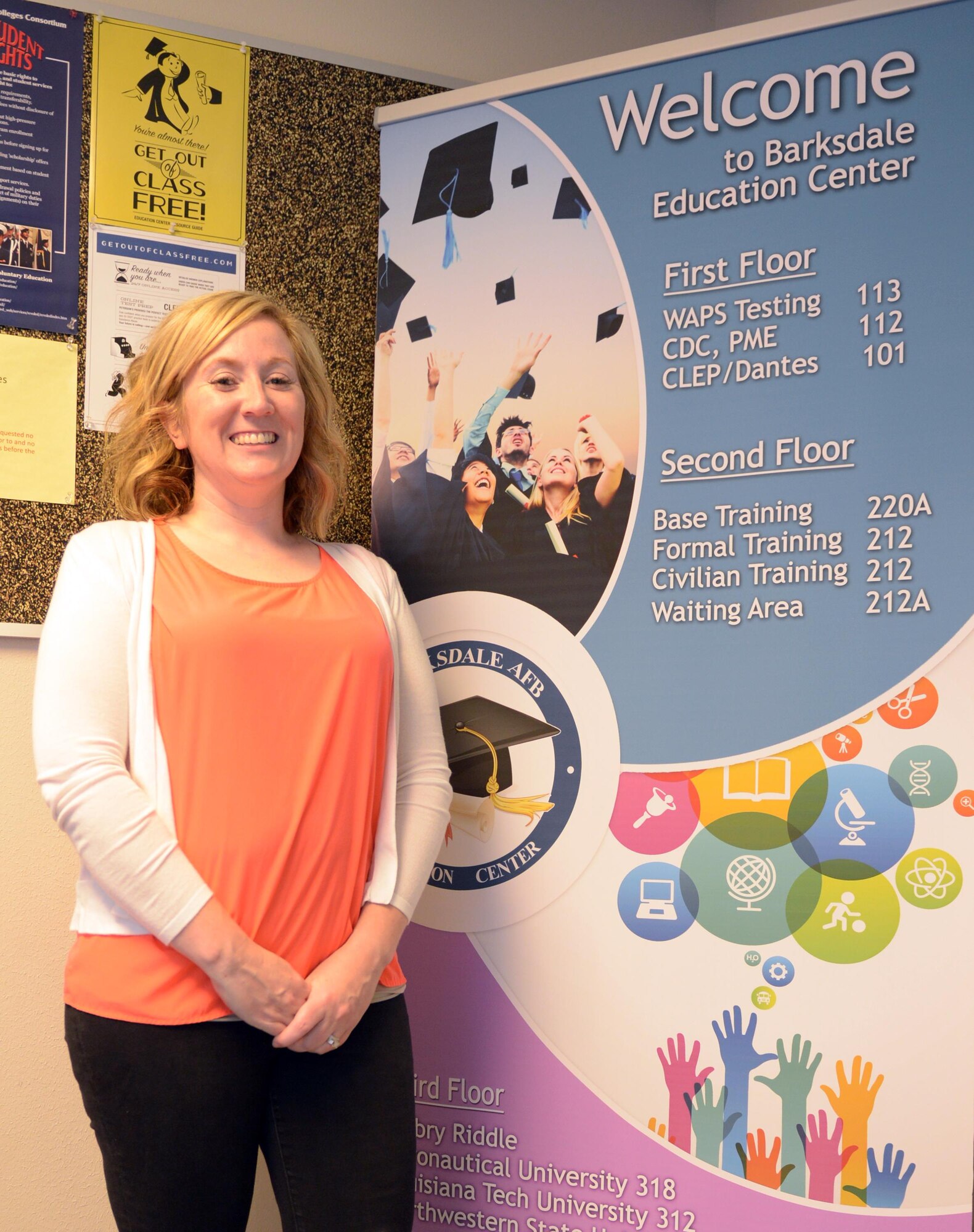Danielle Williams, Education Center counselor, poses for a photo with a new welcome sign at Barksdale Air Force Base, La., Aug. 26, 2016. The Education Center is undergoing a culture change which includes physical restructuring, contract improvements, and a more deliberate approach to highlighting the programs it offers. (U.S. Air Force photo/Senior Airman Curt Beach)