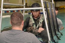 Capt. Mitch Clapp, a pilot assigned to the 54th Helicopter Squadron, prepares for survival, evasion, resistance and escape  egress training at the McAdoo Fitness Center at Minot Air Force Base, N.D., Aug. 31, 2016. The SWET chair, or shallow water egress trainer, simulates an overturned helicopter underwater. (U.S. Air Force photo/Airman 1st Class Jessica Weissman)