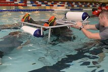 An Airman from the 54th Helicopter Squadron is submerged underwater during survival, evasion, resistance and escape underwater egress training at the McAdoo Fitness Center at Minot Air Force Base, N.D., Aug. 31, 2016. SERE specialists observe Airmen and are prepared to safely release them if they cannot escape the simulated crash. (U.S. Air Force photo/Airman 1st Class Jessica Weissman)