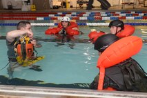 Airmen from the 54th Helicopter Squadron listen to instructions from Staff Sgt. Anthony Barrette, a survival, evasion, resistance and escape specialist assigned to the 5th Operations Support Squadron, during water egress training at the McAdoo Fitness Center at Minot Air Force Base, N.D., Aug. 31, 2016. SERE specialists explained procedures to escape a crashed helicopter and how to properly use common rescue devices used by all branches of the armed forces. (U.S. Air Force photo/Airman 1st Class Jessica Weissman