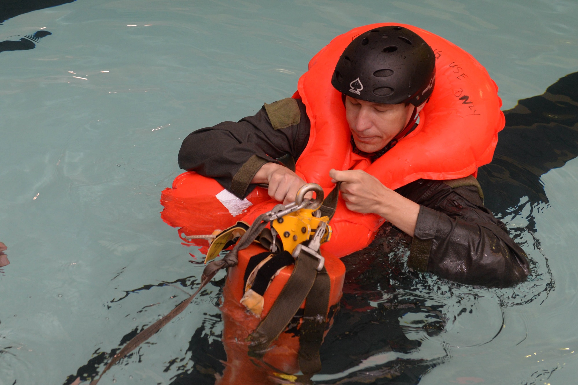 Capt. Mitch Clapp, a pilot assigned to the 54th Helicopter Squadron, hooks himself onto a forest penetrator rescue device during survival, evasion, resistance and escape egress training at the McAdoo Fitness Center at Minot Air Force Base, N.D., Aug. 31, 2016. Devices such as this are used by other branches of the armed forces for recovery during water survival. (U.S. Air Force photo/Airman 1st Class Jessica Weissman) 