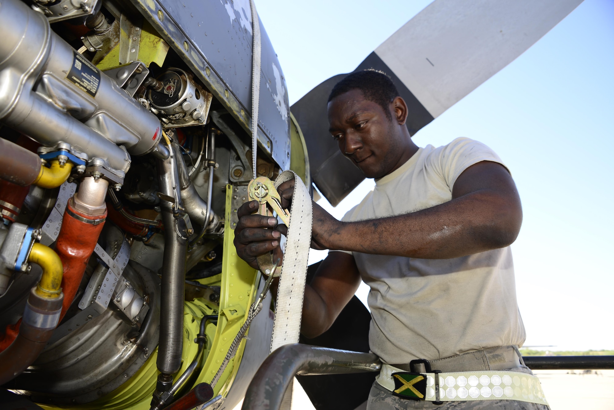 U.S. Air Force Senior Airman George Thompson, 755th Aircraft Maintenance Squadron aerospace propulsion journeyman, tightens a ratchet strap around the engine of an EC-130H Compass Call at Davis-Monthan Air Force Base, Ariz., Aug. 31, 2016. Thompson used the ratchet strap to hold a chin scoop against the base of the aircrafts engine while he and additional members of the 755th AMXS fastened it in place. (U.S. Air Force photo by Senior Airman Betty R. Chevalier)