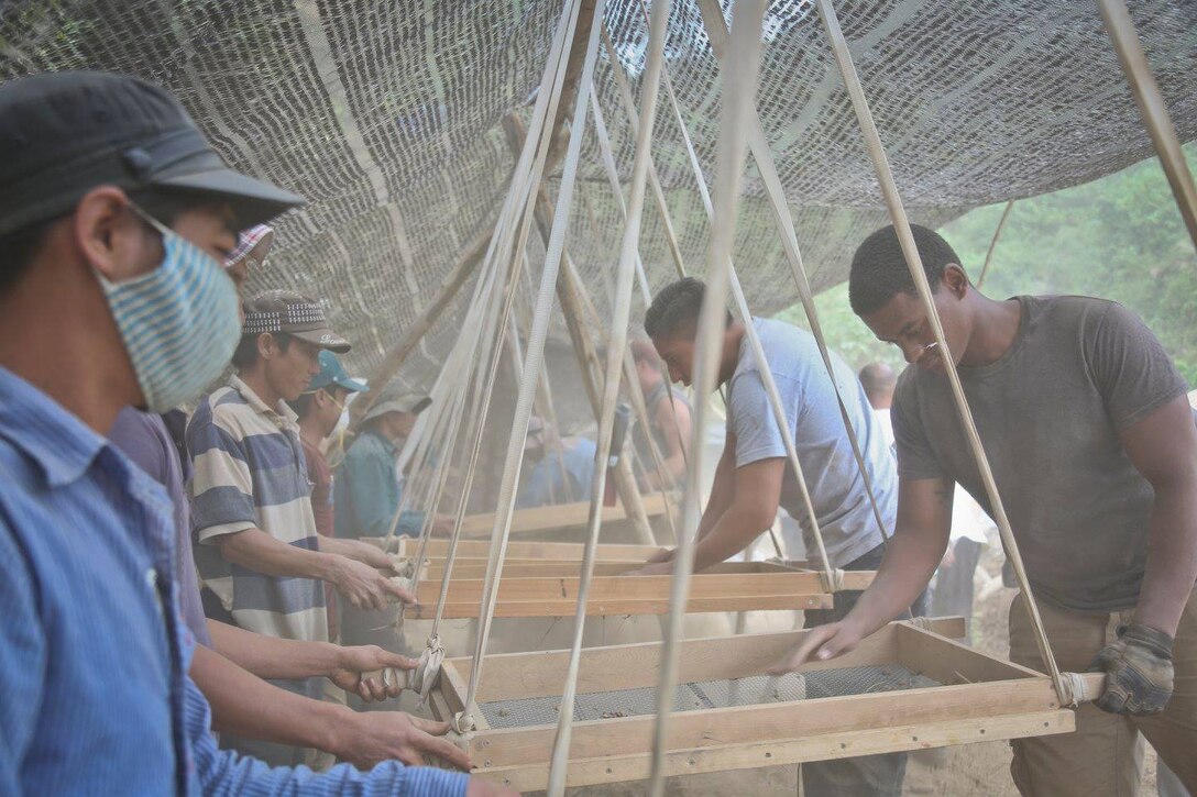 Workers sift dirt during the excavation of a site in Vietnam as part of a search for a missing US service member.