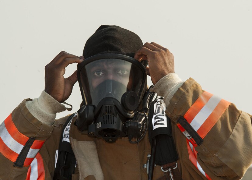 A Minot firefighter puts on his mask at Minot Air Force Base, N.D., Sep. 1, 2016. Along with extinguishing fires, the fire department also drives and operates fire apparatuses, specialized tools, and equipment, conducts hose evolutions and pump operations, and protects exposures, preserves and protects emergency scene evidence, and investigates fires to determine origin and cause. (U.S. Air Force photo/Airman 1st Class Christian Sullivan)