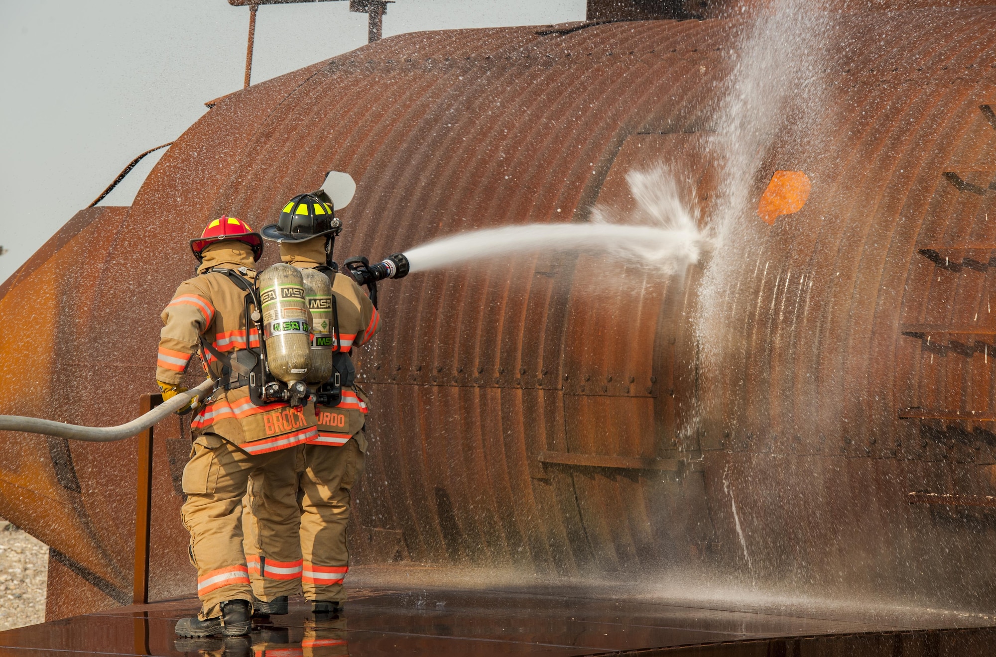 5th Engineer Squadron firefighters spray down an enflamed fire trainer at Minot Air Force Base, N.D., Sept. 1, 2016. The fire protection flight’s goal is to protect people, property and the environment from fires and disasters by providing fire prevention, firefighting, rescue and hazardous material response. (U.S. Air Force photo/Airman 1st Class Christian Sullivan)