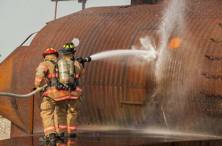 5th Engineer Squadron firefighters spray down an enflamed fire trainer at Minot Air Force Base, N.D., Sept. 1, 2016. The fire protection flight’s goal is to protect people, property and the environment from fires and disasters by providing fire prevention, firefighting, rescue and hazardous material response. (U.S. Air Force photo/Airman 1st Class Christian Sullivan)