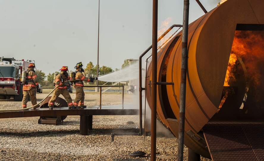 5th Engineer Squadron firefighters spray down an enflamed fire trainer at Minot Air Force Base, N.D., Sept. 1, 2016. The fire protection flight’s goal is to protect people, property and the environment from fires and disasters by providing fire prevention, firefighting, rescue and hazardous material response. (U.S. Air Force photo/Airman 1st Class Christian Sullivan)
