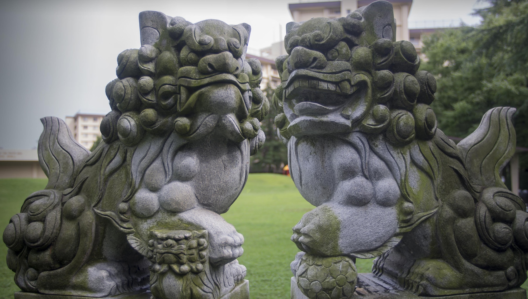 A pair of komainu, or lion-dogs, stand guard outside the Yuko Park and Sakura Shell at Yokota Air Base, Japan, Aug. 30, 2016. Komainu are often placed in front of shrines, gates and houses where they are said to provide protection from evil spirits. Common belief is that the open and closed mouths are derived from Buddhist symbolism. The mouths are shaped forming the sounds “a” and “un” which combine to form “a-un” which is the Japanese rendition of the Indian word 'om.’ Originating in Hinduism and adopted by Buddhism, the word’s meaning seems somewhat vague at times, but is sometimes described as the name of God or the sound of the vibration of the universe. In Japan, “a” and “un” are also symbolic of beginnings and endings, in the same way that Western countries use alpha and omega. (U.S. Air Force graphic by Senior Airman David C. Danford/Released)