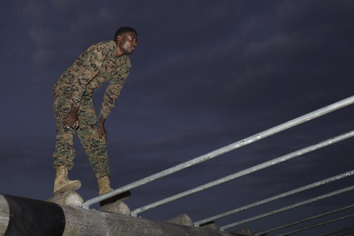 Lance Cpl. Kwesi Thomas, armorer with Marine Aircraft Group 12, waits for a bowl of water while standing on an obstacle within the obstacle course at Marine Corps Air Station Iwakuni, Japan. Marines with MAG-12 ran the obstacle course and received a Professional Military Education lesson on leadership as part of their physical training.  (U.S. Marine Corps photo by Lance Cpl. Abrego)