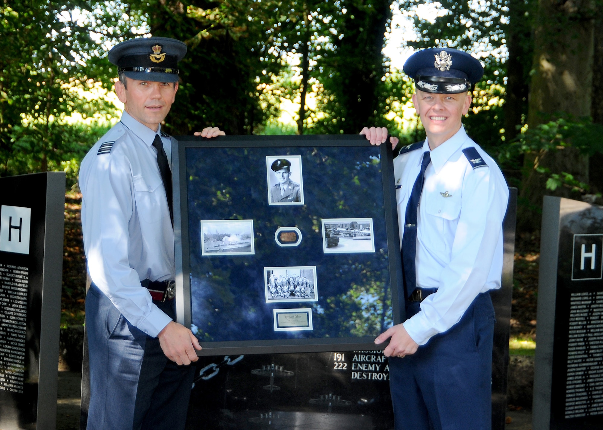 Wing Commander Matt Cornish, officer commanding support wing at RAF Honington, and U.S. Air Force Col. Derek Salmi, 100th Operations Group commander, pose in front of the 388th Bombardment Group, 8th Air Force memorial with a framed World War II U.S. Army Air Forces dog tag that was found while metal detecting on the former RAF Knettishall grounds near Knettishall, England, Aug. 12, 2016. This repatriation of the U.S. service member's dog tag marked the official receipt from the RAF to the U.S. Air Force on behalf of the surviving service member who was assigned to the 388th BG and 8th AF, and is currently living in Louisiana. Following this ceremony, the dog tag will be transported to the 8th AF in Louisiana where it can then be officially presented to its rightful owner. (U.S. Air Force photo by Senior Master Sgt. Brian M. Boisvert)