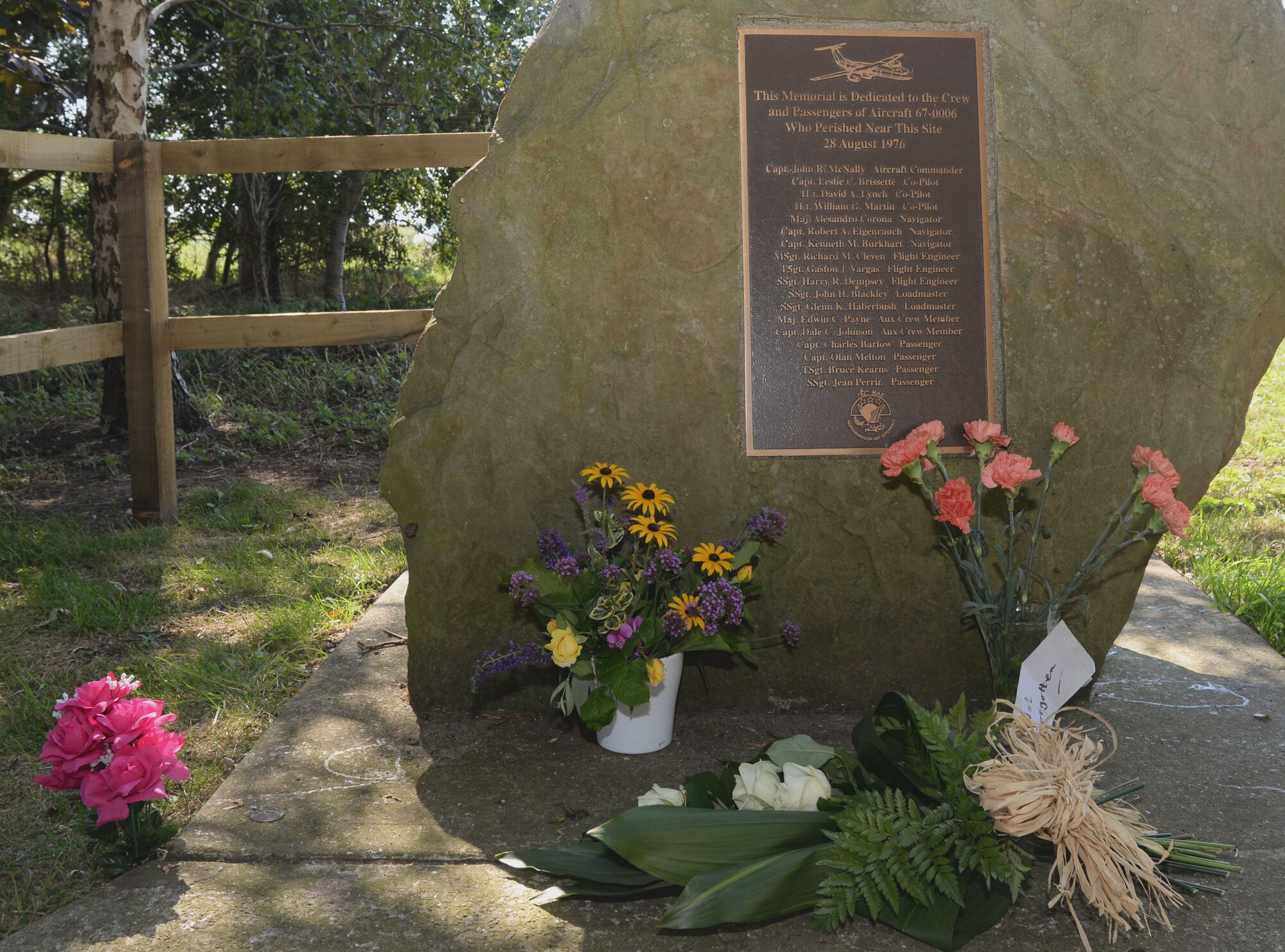 Flowers lay in front of a bronze plaque that reads the names of those lost in an aircraft crash Aug. 28, 1976, in Thorney, England. Local village residents and council members invited Airmen from RAF Mildenhall, England to attend the 40th Anniversary Aug. 30, 2016. All 14 crew members and four passengers died when a C-141 Starlifter from the 438th Military Airlift Wing, McGuire Air Force Base crashed at this location during a severe thunderstorm in route to RAF Mildenhall, England. (U.S. Air Force photo by Senior Airman Justine Rho)