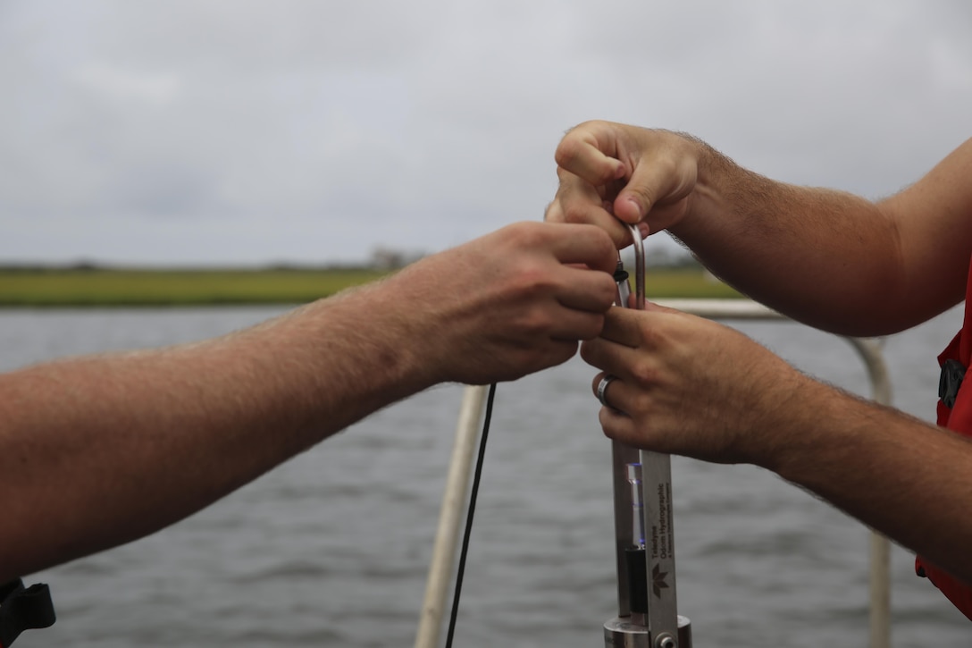 U.S. Marines with Battlefield Surveillance Company, 2nd Intelligence Battalion, tie a cord around a digibar before letting it underwater to collect information such as sound velocity off the coast of Oak Island, N.C., Aug. 31, 2016. The Marines teamed up with U.S. Coast Guardsmen at USCG Station Oak Island, N.C., to create a topographical layout of waterways that were previously unidentifiable. The new maps will correct navigation discrepancies such as off-station buoys or extinguished lights. (U.S. Marine Corps photo by Cpl. Kaitlyn V. Klein)