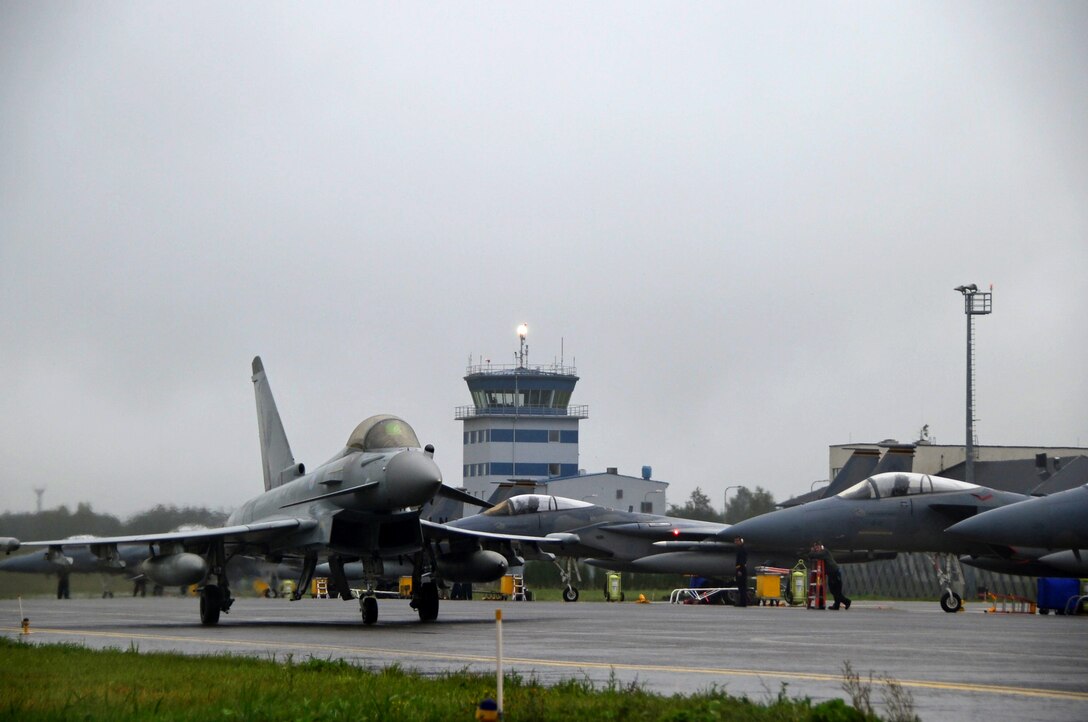 A Royal Air Force Typhoon passes a fleet of F-15C Eagles at Ämari Air Base, Estonia, Aug. 17, 2016. Five countries, including the U.S., U.K., Estonia, Sweden and Finland, participated in a flying training deployment, which allowed for various aircraft and Airmen to test their capabilities against each other in a realistic training environment. (U.S. Air Force photo by Senior Airman Erin Trower/Released)