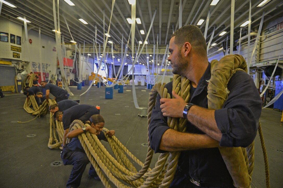 Navy Petty Officer 3rd Class Ahmed N. Abdarbo leads a group of sailors transporting a bundle of shifting lines through the hangar bay aboard the amphibious assault ship USS Iwo Jima in the Atlantic Ocean, Sept. 1, 2016. Navy photo by Petty Officer 3rd Class Jered C. Wallem