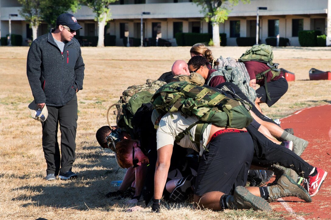 GoRuck instructor, left, coaches service members to make a human bridge at Travis Air Force Base, Calif., Aug. 26, 2016. Air Force photo by Louis Briscese