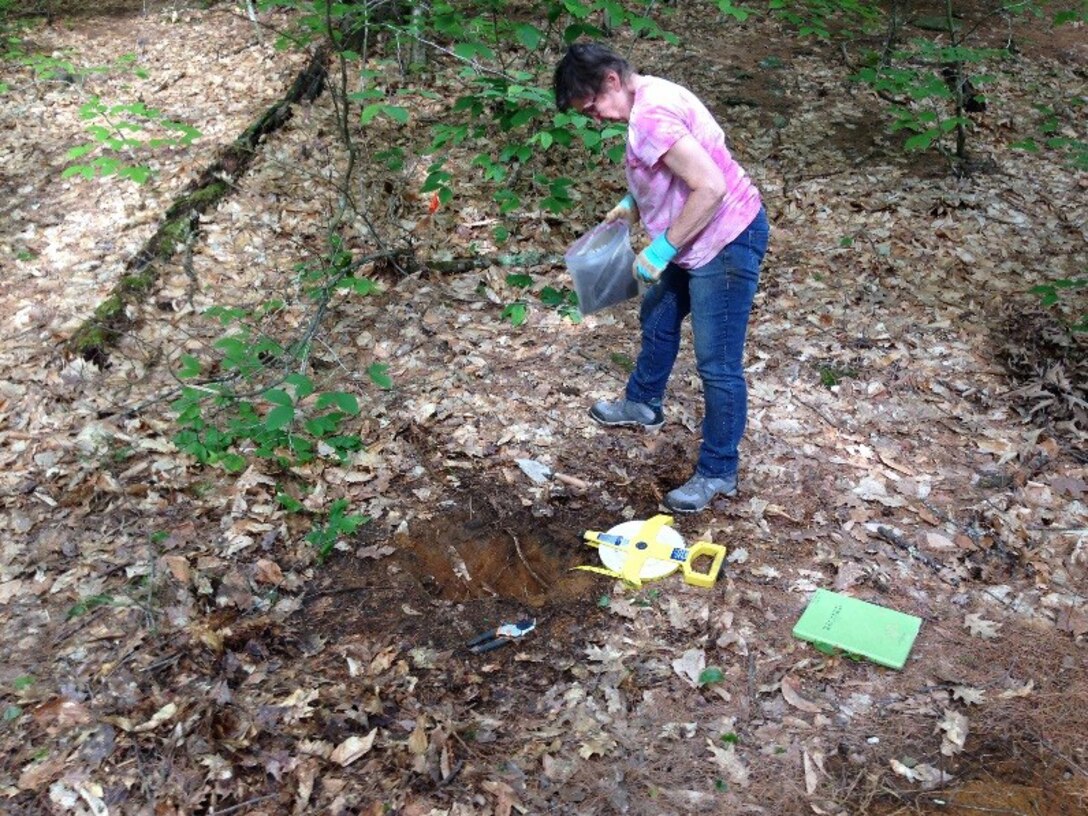 Kate Atwood removes material from a test pit for analysis.