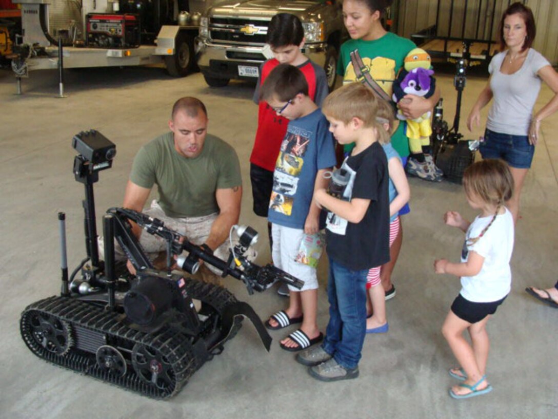 SSgt George Maize demonstrates the capability of a remote operated robot used in defusing unexploded ordnance at the EOD Compound on Aug. 31, 2016 for schoolchildren visiting the facility.