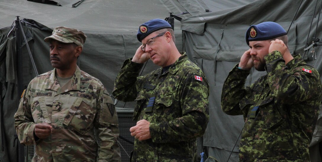 FORT MCCOY, Wis. - Canadian Deputy Surgeon General Scott McLeod (center) and Capt. Kenneth Hiscock (right), health care administrative officer, 1 Field Ambulance, insert their ear protection during a helicopter medical evacuation simulation Aug. 20 during Combat Support Training Exercise 86-16-03 at Fort McCoy, Wis. (U.S. Army Reserve photo by Staff Sgt. Debralee Best)