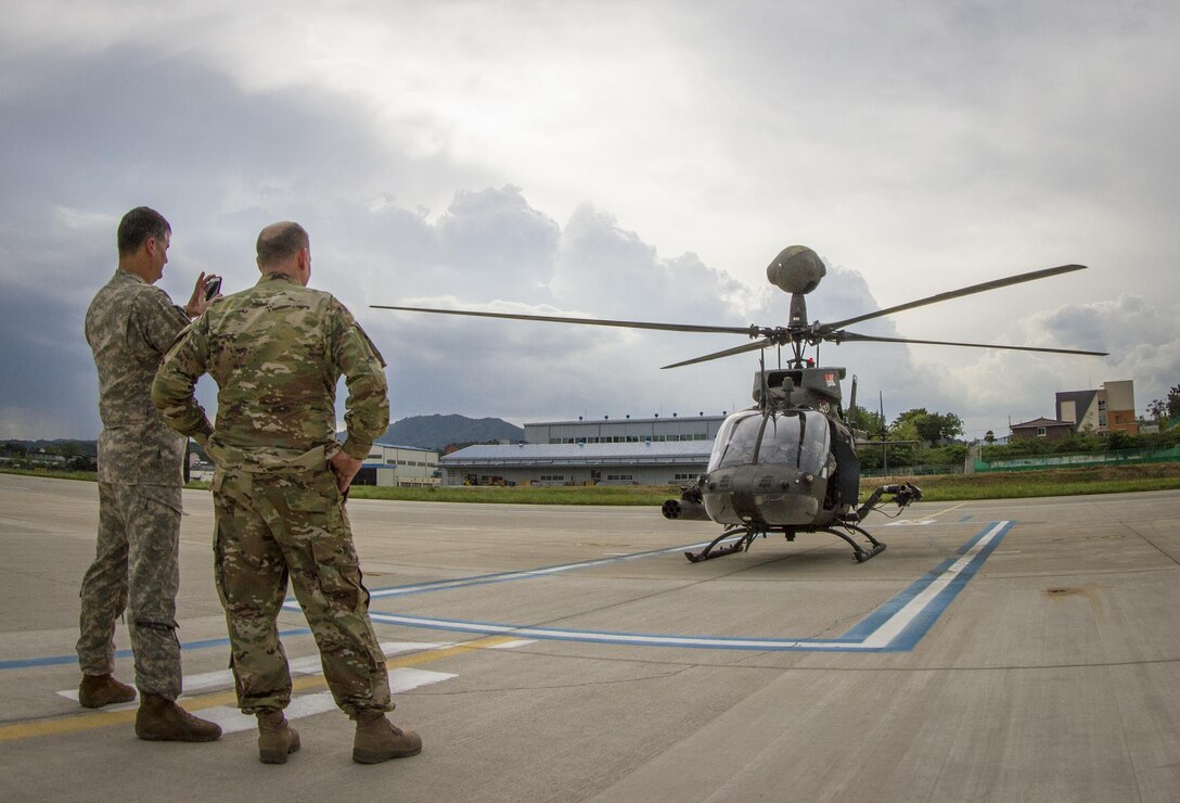 U.S. Army I Corps Chief Warrant Officer 4 Rian Demery (left) takes a photo of an OH-58D Kiowa Warrior as Col. Michael Harvey looks on at an airfield in Yongin, South Korea, Aug. 29, 2016. Both men have thousands of hours of experience flying the OH-58 for the. The helicopter pictured here belongs to the 1st Squadron, 17th Cavalry Regiment, the last squadron of OH-58's. Once the 1-17th's current rotation is over the Army will retire all OH-58's from its fleet. (U.S. Army photo by Staff Sgt. Ken Scar)