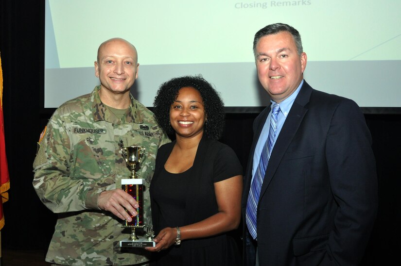 Radiah Scott represents trophy recipient Michael Brown of U.S. Army Center for Initial Military Training, who received the most hourly fitness points with a total of 200.75 during the six-month Fort Eustis Civilian Fitness Commander’s Cup Challenge, at an awards ceremony at Fort Eustis, Va., Aug. 31, 2016.  She is joined by Senior Commander, Maj. Gen. Anthony C. Funkhouser and U.S. Army Training and Doctrine Command G-1/4 Assistant Deputy Chief of Staff Hugh Davis. (U.S. Army photo by Stephanie Slater)