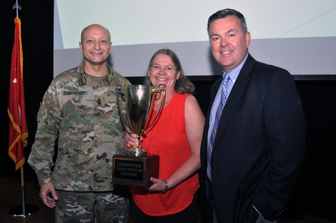 Ruth Wallace accepts the Civilian Commander's Cup on behalf of Fort Eustis Army Community Service, the winners of the six-month Eustis Civilian Fitness Commander’s Cup Challenge at an awards ceremony at Fort Eustis, Va., Aug. 31, 2016. She is joined by Senior Commander, Maj. Gen. Anthony C. Funkhouser and U.S. Army Training and Doctrine Command G-1/4 Assistant Deputy Chief of Staff Hugh Davis. (U.S. Army photo by Stephanie Slater)