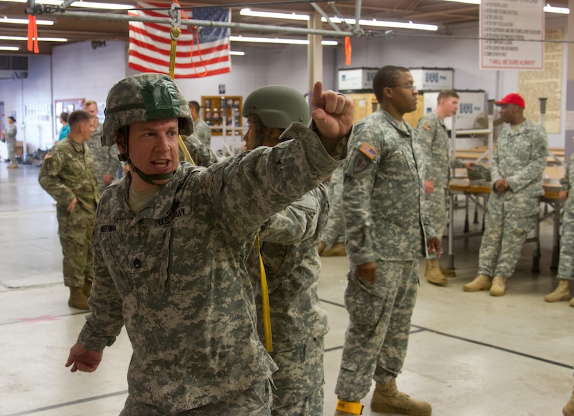 Staff Sgt. Travis Merryman, from Mt. Juliet, Tennessee, signals to other patachute riggers from the 861st Quartermaster Company during training to prepare for a jump later in the day Saturday, Aug. 27, at Fort Campbell, Kentucky.