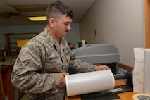 Senior Airman Michael Muldoon, a structural journeyman assigned to the 5th Civil Engineer Squadron, places reflective vinyl onto the holder at Minot Air Force Base, N.D., Aug. 10, 2016. Depending on the size of the template, this 150-foot roll of vinyl will create any number of signs for different units on base. (U.S. Air Force photo/Airman 1st Class Jessica Weissman)