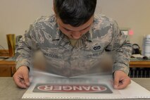 Senior Airman Michael Muldoon, a structural journeyman assigned to the 5th Civil Engineer Squadron, places transfer tape onto a new sign at Minot Air Force Base, N.D., Aug. 10, 2016. Muldoon recently created over 60 new signs for the power production shop. (U.S. Air Force photo/Airman 1st Class Jessica Weissman)