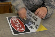 A structural journeyman from the 5th Civil Engineer Squadron lays a new sign onto recycled metal at Minot Air Force Base, N.D., Aug. 10, 2016. The recycled metal was provided by Airmen from the 5th CES power production shop for their new signs.  (U.S. Air Force photo/Airman 1st Class Jessica Weissman)