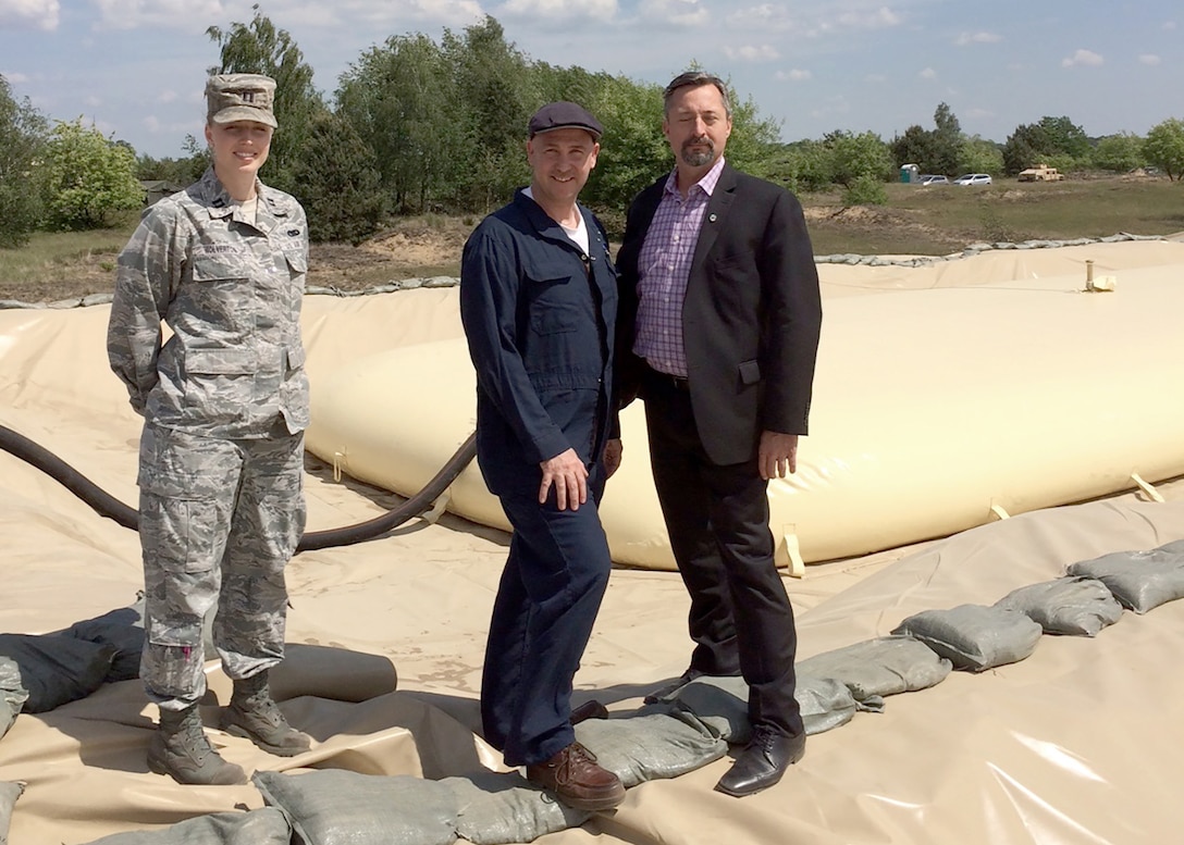 (L-R) Operations officer Air Force Capt. Kristen Wolverton, Quality Assurance Representative Curtis Stough and DLA Energy Europe & Africa liaison officer to USAREUR Mark Knapp stand in front of a 50,000-gallon bag of JP-8, or aviation grade fuel, at the fuel system supply point in Torun, Poland. The DLA Energy team provided subject matter expertise in an advisory role to the USAREUR site.