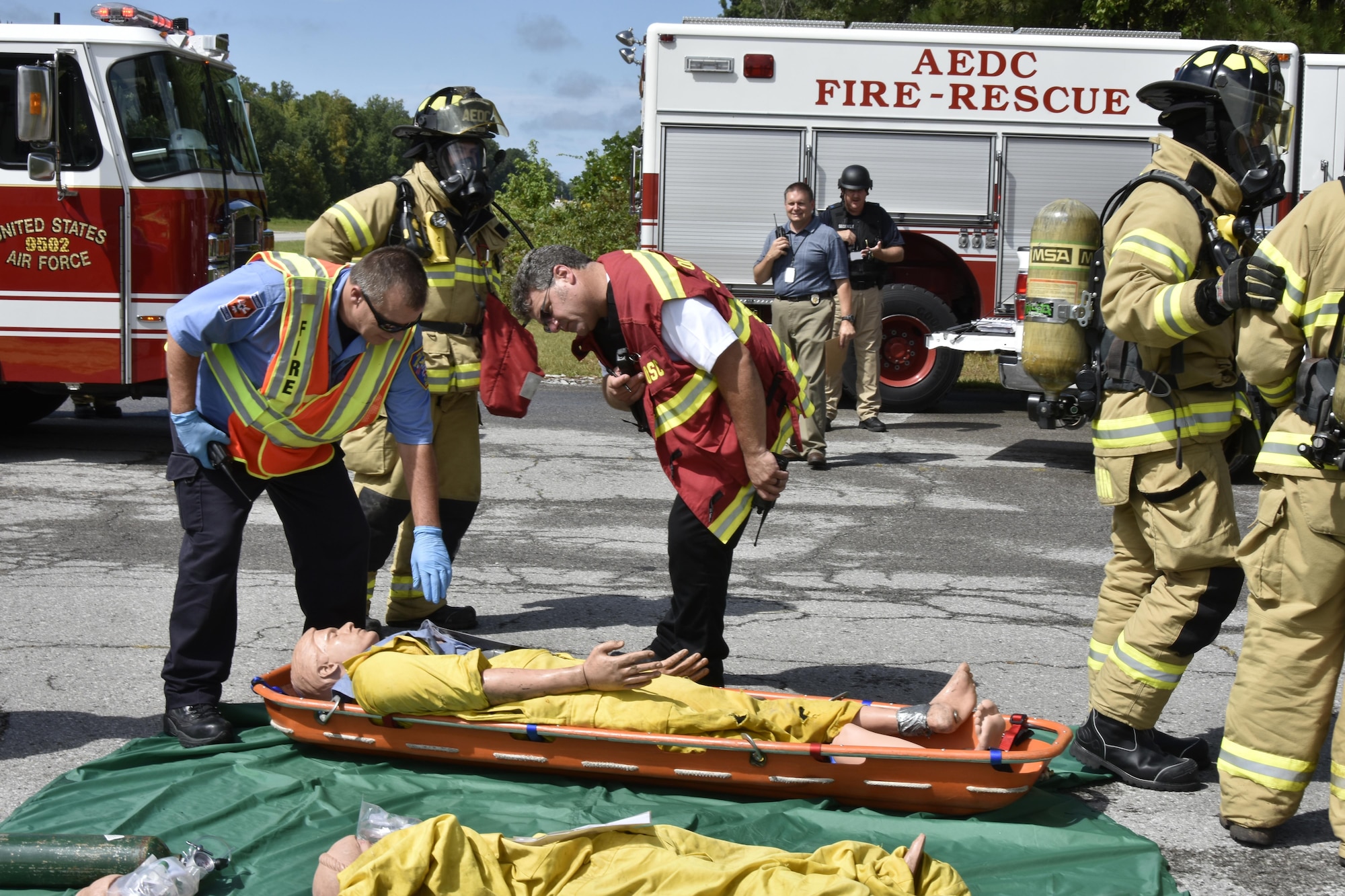 AEDC Fire-Rescue team members simulate examining training mannequins during the emergency base exercise.