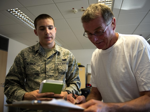 U.S. Air Force Senior Airman Jonah Webber, 52nd Communications Squadron client systems technician, left, points out information on a checklist to Jim Leahy, 52nd Logistics Readiness Squadron functional systems administrator, right, at the cargo deployment facility on Spangdahlem Air Base, Germany, Sept. 7, 2016. Webber, a recent graduate from Pitsenbarger Airman Leadership School, is using knowledge learned from ALS at his workplace, such as understanding different leadership styles, negotiating tactics and how to handle situations. (U.S. Air Force photo by Airman 1st Class Preston Cherry/Released)